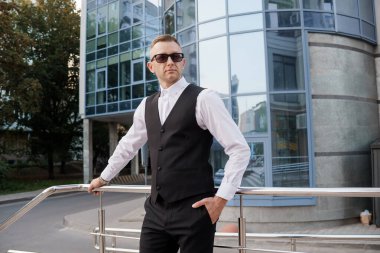 Şık iş adamı şehir ortamında güven içinde poz veriyor..