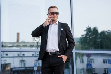 Güneş gözlüklü sofistike iş adamı kendine güvenen bir telefon görüşmesi yaptı..