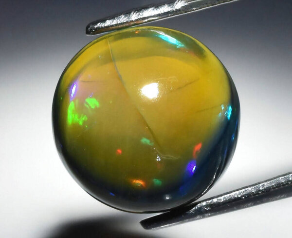 Captivating Display of a Glossy Natural Gemstone with Iridescent Colors and Unique Surface Characteristics.