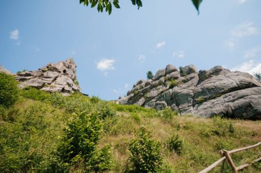 Parlak Mavi Gökyüzü Altında Görkemli Kaya oluşumları Çevrelenmiş Yeşillik.