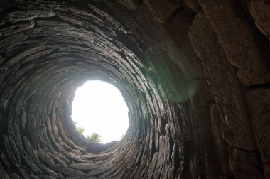 Gökyüzüne uzanan antik bir taş kuyusunun dramatik bir perspektifi.