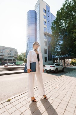 Çizgili Takım Elbiseli Zarif İş Kadını Modern Ofis Binası 'nın önünde kendinden emin duruyor..