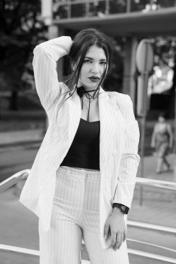 Çizgili Takım Elbiseli Şık Genç Kadın Şehir Ortamına Emin Bir Poz Veriyor.