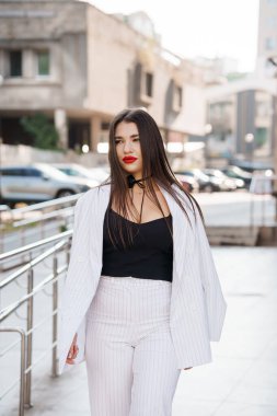 İnce çizgili takım elbiseli şık bir kadın Kentin caddesinde güven içinde yürüyor..