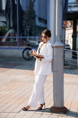 Diz üstü bilgisayarlı şık çizgili takım elbiseli kendine güvenen iş kadını..