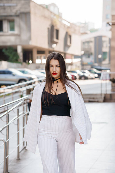 Городская мода Элеганта: уверенная женщина в полосатом костюме по городу.