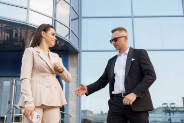 Modern bir ofis binasının dışında dostça bir toplantıya katılan İş Profesyonelleri.