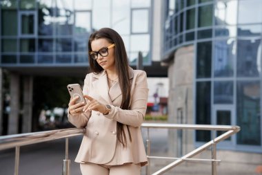 Modern bir ofis binasının önünde zarif giyimli bir iş kadını Mobil İletişim 'e girdi..