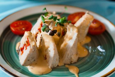 Exquisite Gourmet Chicken Roulade with Creamy Sauce and Fresh Tomato Garnish.