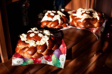 Three Beautifully Decorated Sweet Breads with Floral Buttercream Accents on a Wooden Table. clipart