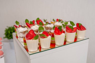 Exquisite Mini Dessert Cups Decorated with Fresh Strawberries and Mint Leaves. clipart