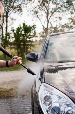 Bir Kişinin Kapalı Çekimi Siyah Araba Temizlemek İçin Basınç Makinesi Kullanılarak Açık Hava Ayarlarında Detaylı.