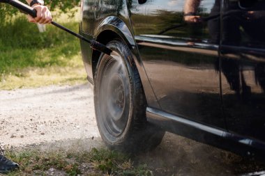 Siyah bir Araba Tekerleği 'nin Yakın Çekimi Bir Basınç Temizleyicisi ile Temizleniyor.