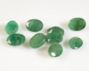 Beyaz bir yüzeyde gösterilen zarif Parlak Yeşil Zümrüt Taşları Koleksiyonu.