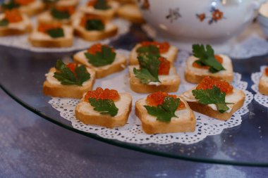 Havyarlı zarif kanepeler ve dekoratif bir tabakta taze bitkiler..