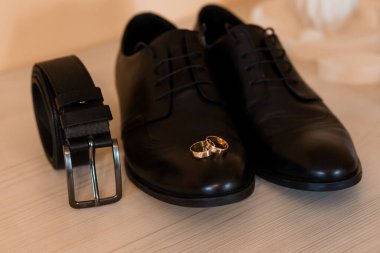 Siyah Ayakkabılar, Kuşak ve Alyanslar içeren Klasik Aksesuarlı Şık Düğün Giysileri.