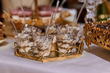 Süslü cam bardaklarda katmanlı çikolata ve krema içeren zarif bir tatlı gösterisi..