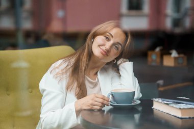 Samimi bir kafede kahve içen bir kadının huzur yansıması..