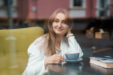 Portrait of a Smiling Woman Enjoying Coffee in a Cafe Setting. clipart