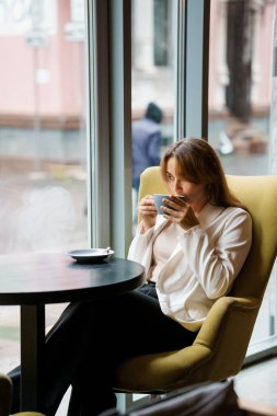 Huzurlu bir an: Bir kafede kahvesinin tadını çıkaran bir kadın.