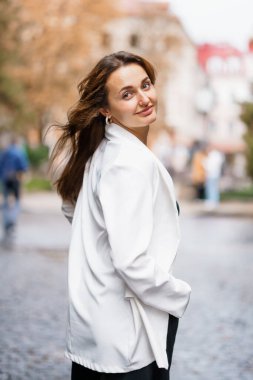 Akan beyaz ceketli güzel kadın şehir ortamında gülümsüyor..