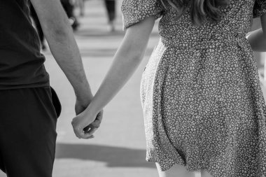 Siyah beyaz bir caddede romantik bir çift el ele tutuşuyor..