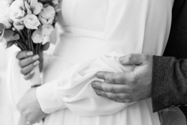 Siyah ve Beyaz Buketi Tutan Yeni Evlilere Romantik Kucaklaşma.