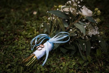 Altın Yüzüklü Zarif Düğün Buketi Lush Green Grass 'ta Mavi Kurdeleyle Bağlı.