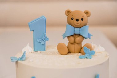 Sevimli bir ilk doğum günü pastası Sevimli bir ayı ve dekoratif kelebeklerle süslenmiş.