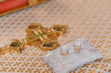 Altın Haç 'ın yanında Dekoratif Yastık Üzerine Zarif Evlilik Yüzükleri.