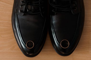 Parmak uçlarında alyansları olan şık siyah ayakkabılar..