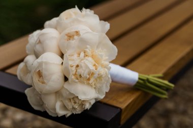 Kırsal ahşap bir bankta Beyaz Şakayık Gelin Buketi.