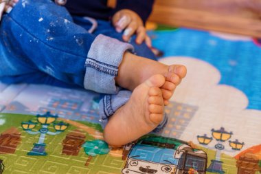 Yalınayak Yürüyen Bebek Renkli Çizimlerle Oyun Mat 'inde Oturuyor.