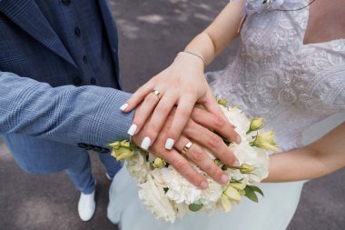 Sarmaş dolaş elleri ve çiçekli romantik bir düğün anı.