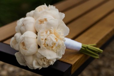 Kırsal ahşap bir bankta Beyaz Şakayık Gelin Buketi.