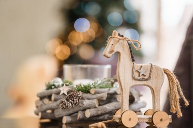 Festive Wooden Toy Horse with Decorated Wreath and Bokeh Background. clipart