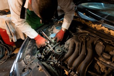 Mechanic Performing Engine Repair in a Dimly Lit Garage. clipart