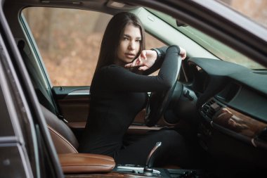 Zarif bir arabada güzel bir kadın, doğal bir ortamda kendine güven ve zarafet yayıyor..