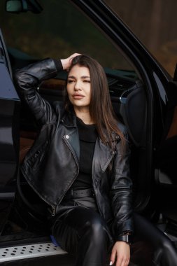 Deri Ceketli Şık Kadın Doğada Bir Araba Kapısı Fotoğrafı.
