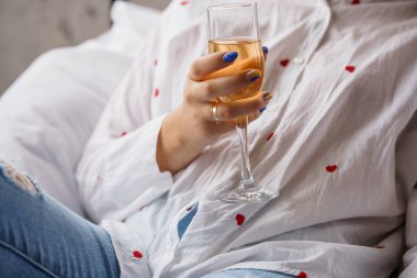 Sıradan giyinmiş bir kadın, koltukta dinlenirken bir bardak köpüklü içeceğin tadını çıkarıyor..