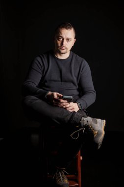 Bir sandalyede oturan düşünceli bir adamın portresi Karanlık bir ortamda telefonla..