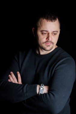 Koyu renk elbiseli, kolları çaprazlanmış tefekkür eden adam..