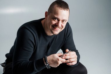 Oyuncak gülüşlü, elinde kalem tutan karizmatik adam..