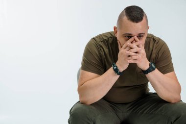 Düşünceli bir adam, günlük giysiler içinde elleri ve yüzlerini kapatarak oturuyor. Düşüncelerini ifade ediyor..