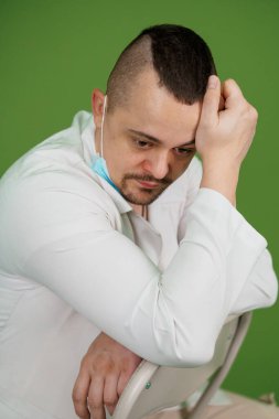 Klinik Çevrede Zorlukları Yansıtan Dalgın Bir Sağlıkçı.