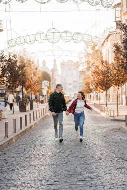 Güzel bir kaldırım taşı caddesinde el ele gezen neşeli çift..