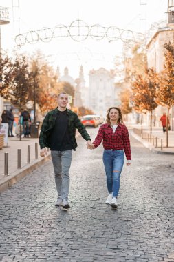 Büyüleyici bir çift, Sonbaharda Resimli Şehir Sokağında El ele Geziniyor.