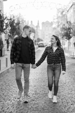 A Charming Black and White Moment of a Couple Walking Hand in Hand on a Cobblestone Street. clipart