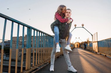 Romantik çift gün batımında şehir köprüsünde neşeli bir anın tadını çıkarıyor..