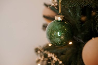 Sparkling Green Ornament Hanging on a Christmas Tree. clipart